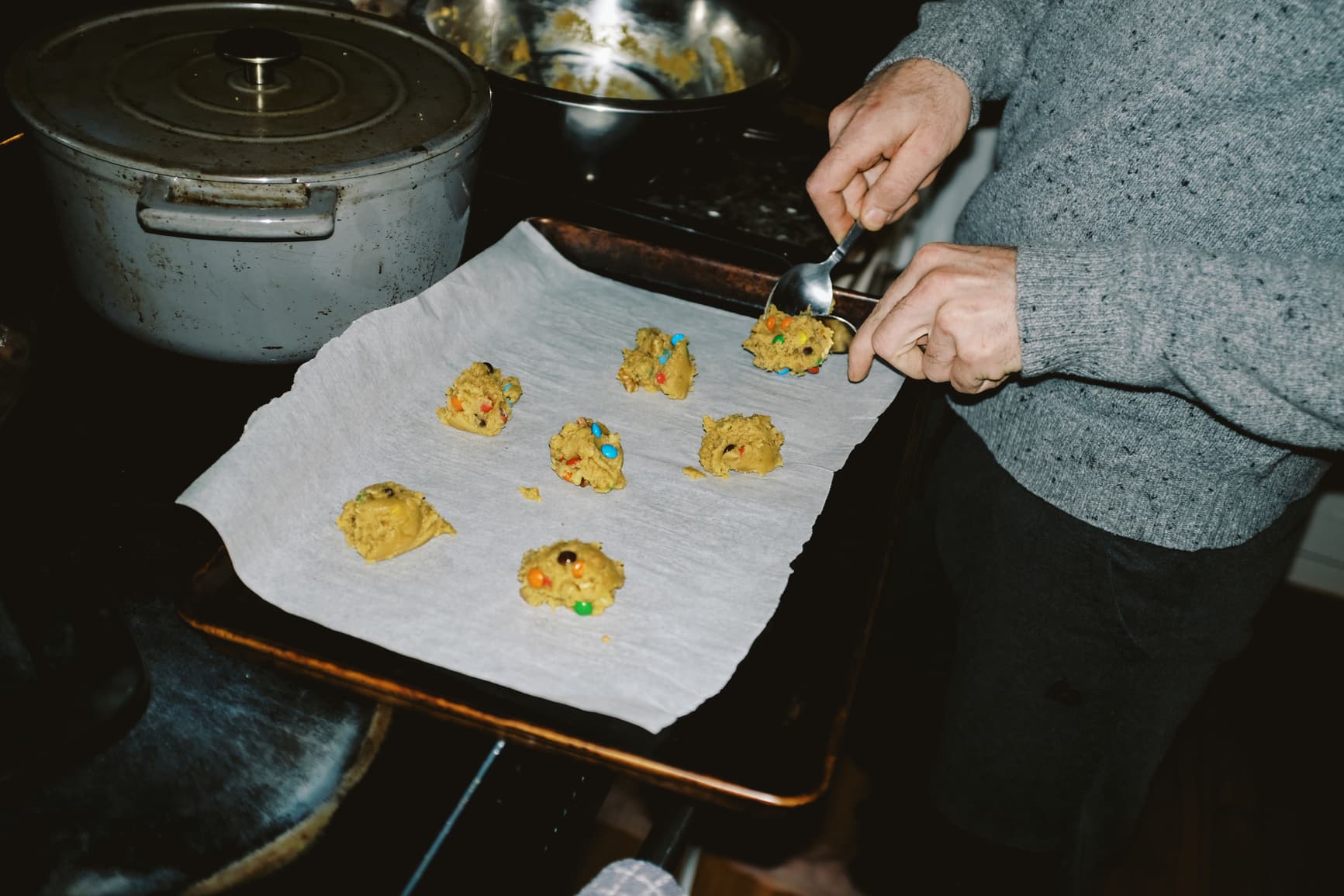 Spooning cookie dough with candy onto a baking sheet