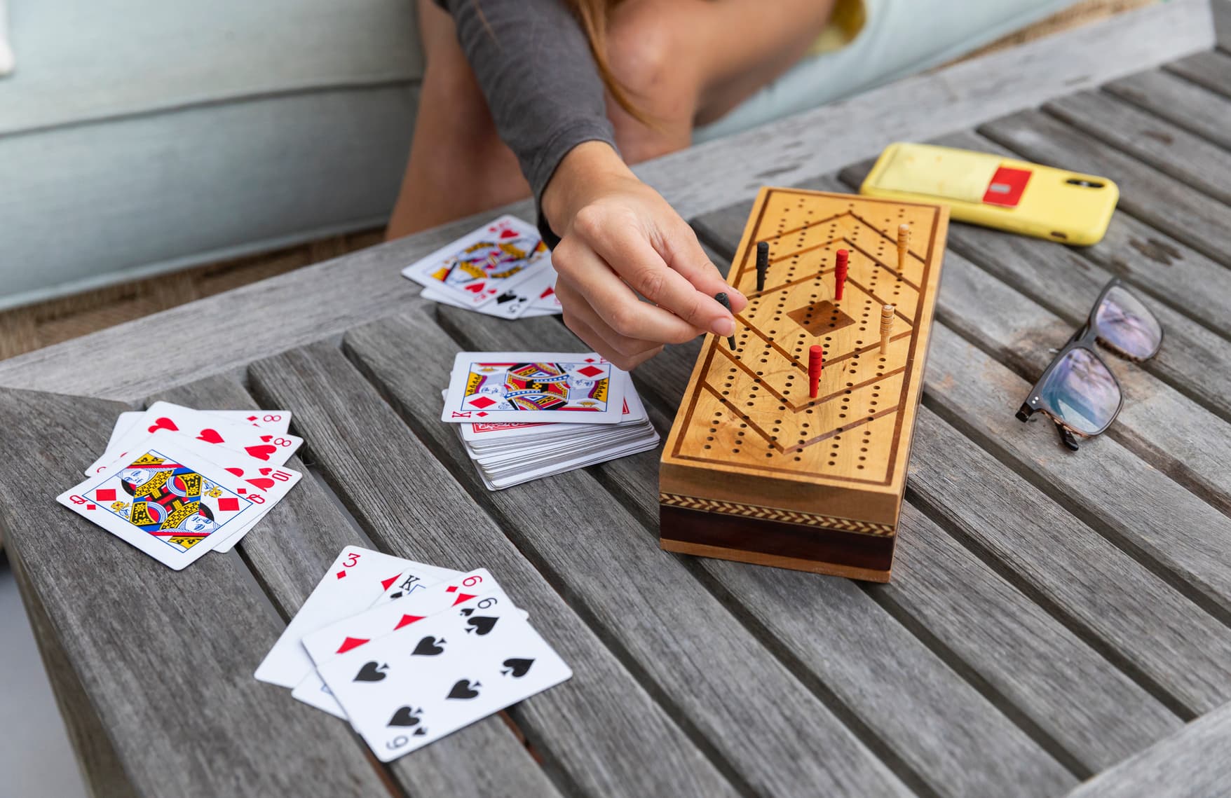 Hands playing cribbage with cards on a table