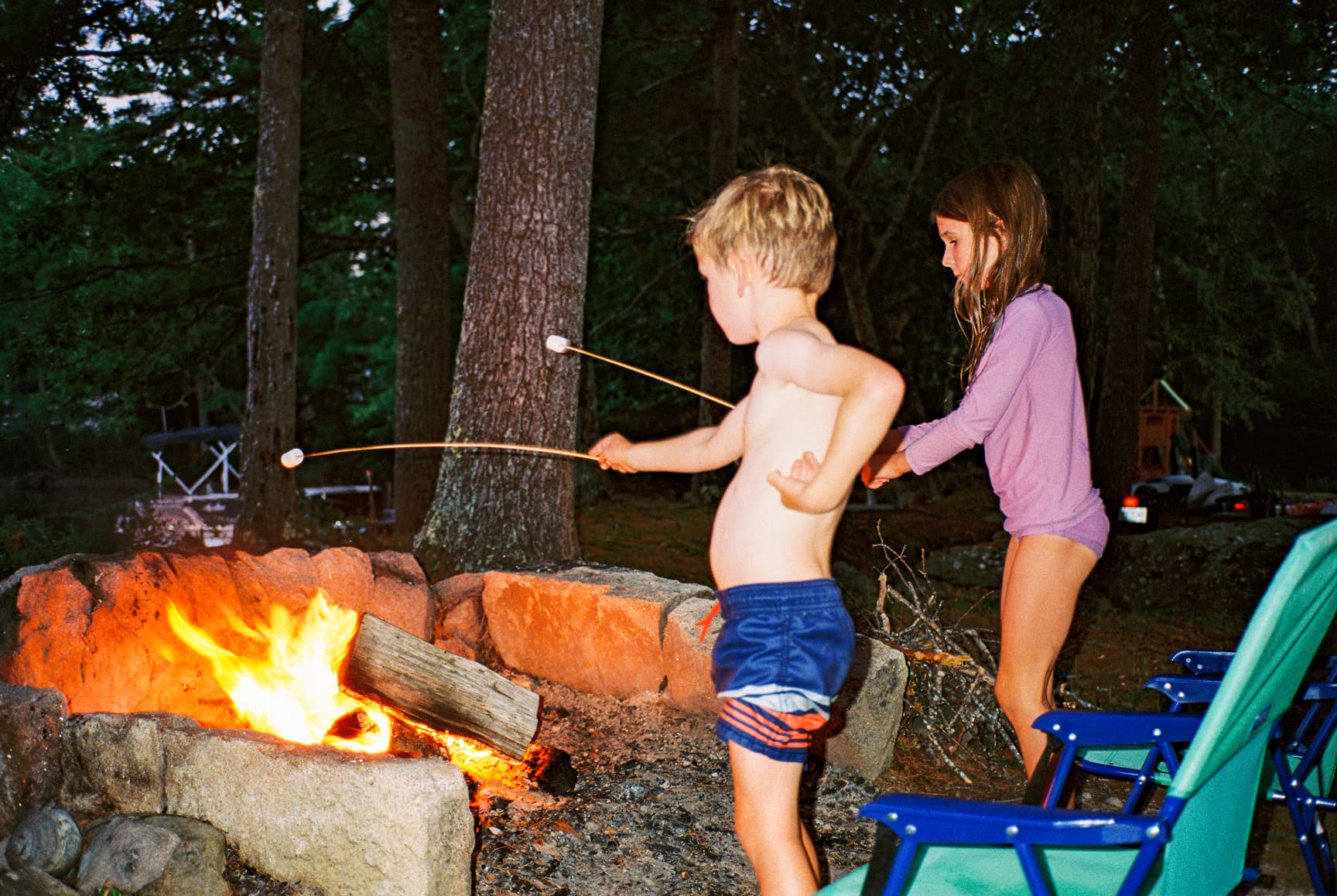 Two kids roasting marshmallows at a bonfire