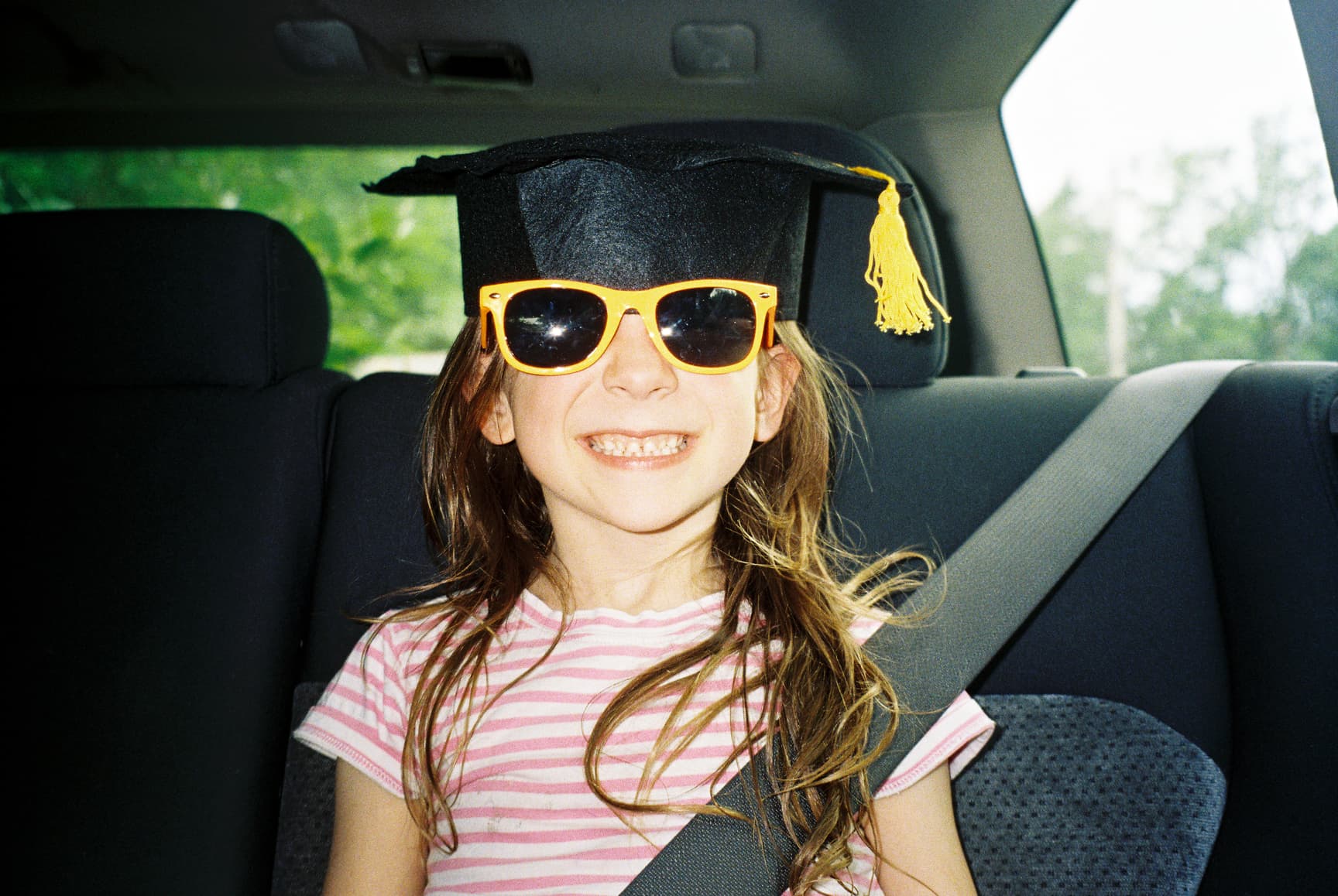 Young girl wearing a graduation cap and sunglasses